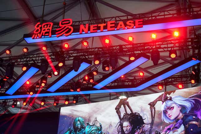 A red NetEase hangs in front of red stage lights. 