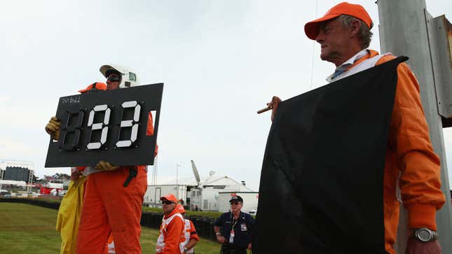 A photo of a marshal holding up a black flag during an auto race. 