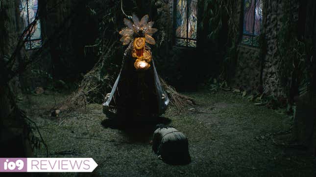 A woman in an elaborate costume holds a glowing object over a bowing child