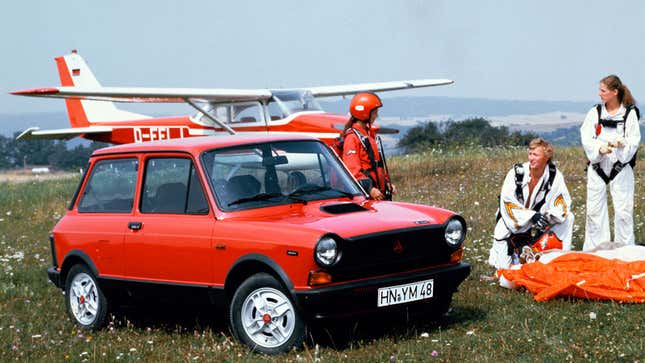 A red Autobianchi with two pilots standing next to it. 