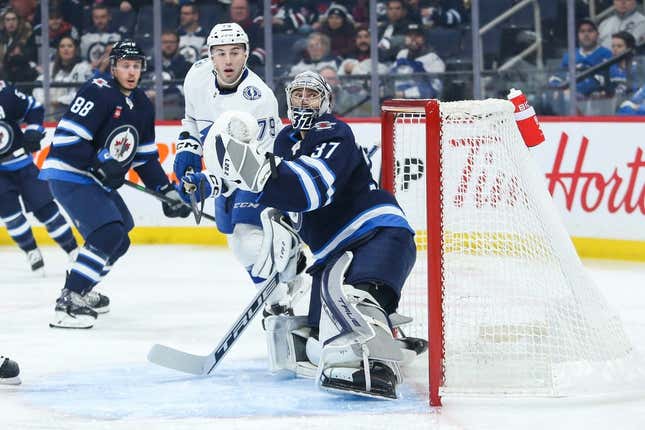 Jan 6, 2023; Winnipeg, Manitoba, CAN;  Tampa Bay Lightning forward Ross Colton (79) and Winnipeg Jets goalie Connor Hellebuyck (37) look for the puck during the first period at Canada Life Centre.