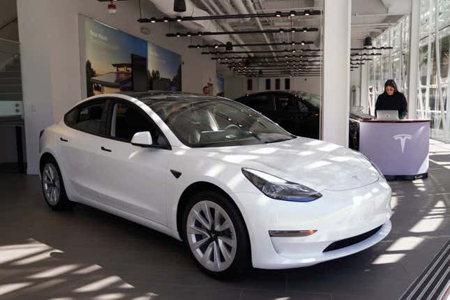 A white Tesla parked at a Tesla showroom floor.