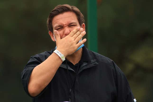 Ron DeSantis covers his mouth with his hand. 