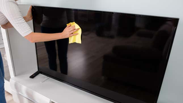 Woman wiping TV screen with a cloth
