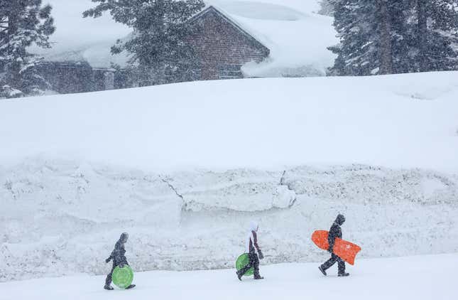 People walk past snowbanks piled up in Mammoth Lakes, CA.