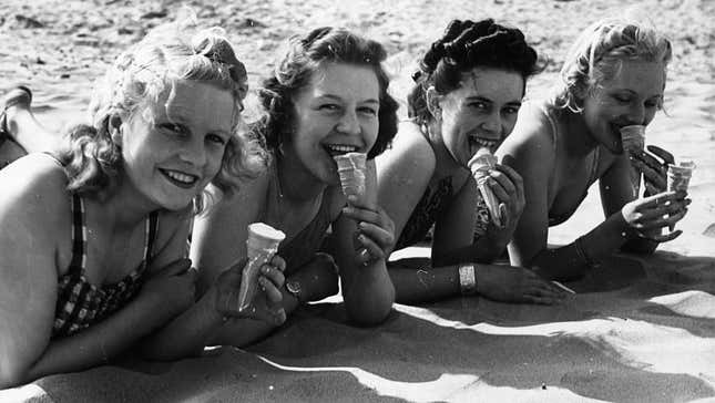 Black & white vintage photo of people in swimsuits on the beach eating ice cream cones