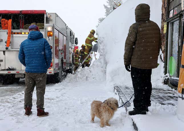 People watch as Mammoth Lakes Fire Department firefighters respond to a propane heater leak and small fire at a shuttered restaurant surrounded by snowbanks, on March 12, 2023 in Mammoth Lakes, California.