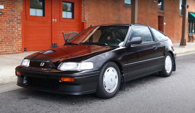 Ein schwarzer Honda CRX, Baujahr 1988, parkt vor einem Backsteingebäude.