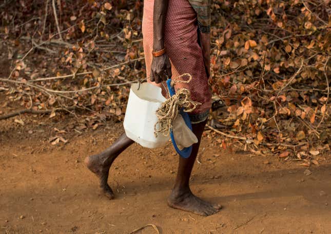A woman carries an improvised plastic can to fetch water from a well outside Denganmal village