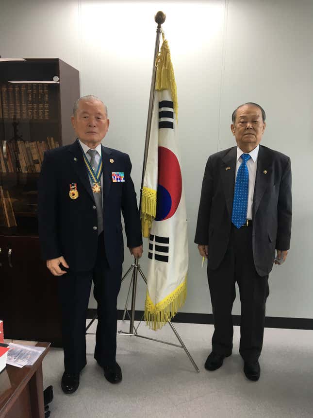 Kim Jong-hwan, left, and Kim Seong-yeol in front of the South Korean flag.