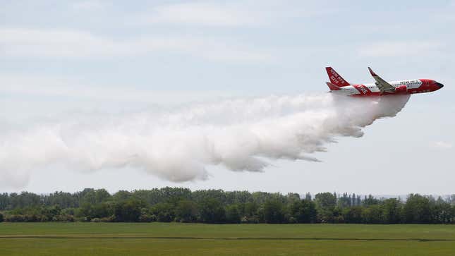 A photo of a Boeing 737 dropping water on a field. 