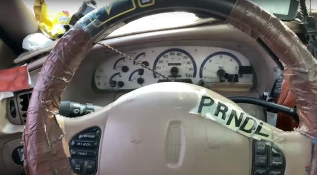 A steering wheel is covered in tape, with PRNDL stuck onto the airbag.