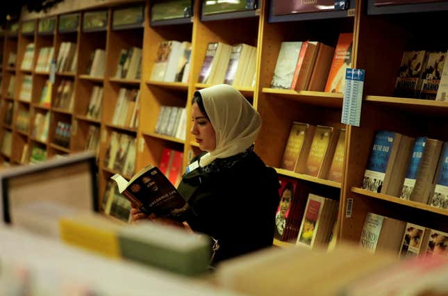 A woman in a headscarf reading in a bookshop