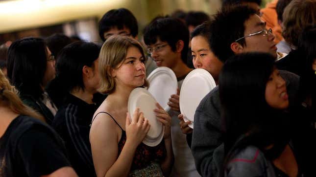 Students waiting in line for food holding plates