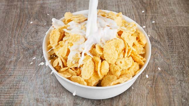 Milk poured over bowl of healthy flakes cereal
