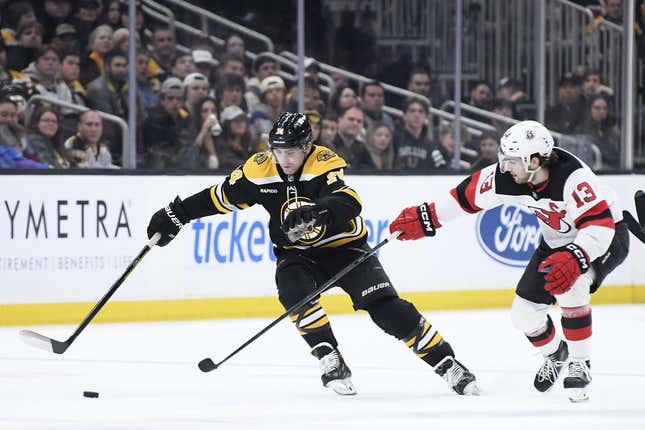 Apr 8, 2023; Boston, Massachusetts, USA;  New Jersey Devils center Nico Hischier (13) tries to poke the puck away from Boston Bruins left wing Jake DeBrusk (74) during the first period at TD Garden.