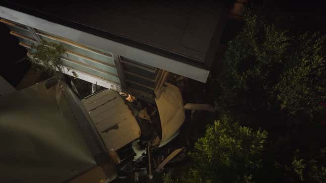 A photo of a delivery truck crashed into the side of a house.