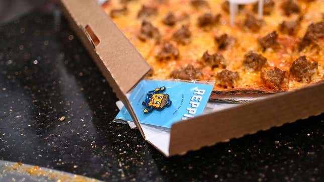 Pizza in box with an enamel pin bearing the Crust Fund PIzza logo