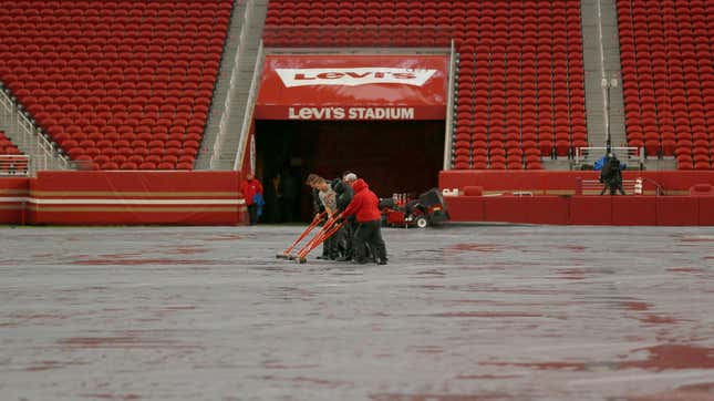 Workers push water off a tarp covering the field from rain at Levi's Stadium before an NFL football game between the San Francisco 49ers and the Indianapolis Colts in Santa Clara, California.