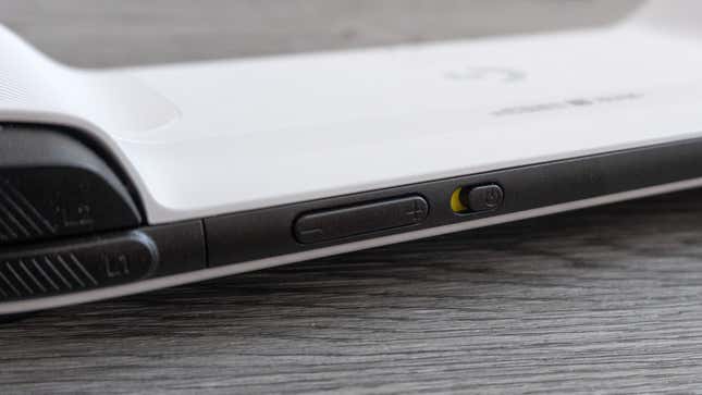 A close up of the top edge of the Logitech G Cloud highlighting the volume rocker and sliding power switch against a gray wooden background.