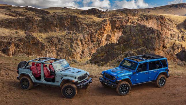 A light teal Jeep Wrangler Unlimited 4-door Rubicon with the doors off, parked head to head with a bright blue Jeep Wrangler Unlimited Rubicon  with the sunroof open on a mountain landscape