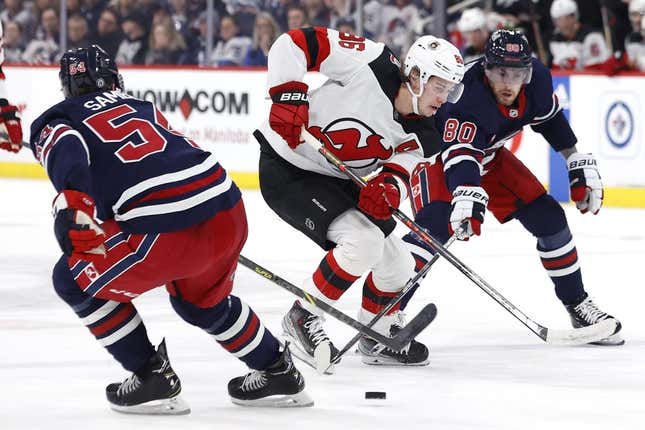 Apr 2, 2023; Winnipeg, Manitoba, CAN; New Jersey Devils center Jack Hughes (86) is checked by Winnipeg Jets defenseman Dylan Samberg (54) and Winnipeg Jets left wing Pierre-Luc Dubois (80) in the first period at Canada Life Centre.