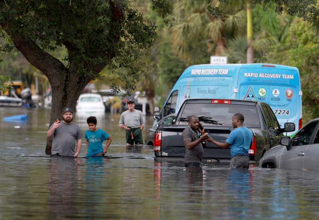 People walk through a flooded neighborhood on April 13, 2023 in Fort Lauderdale, Florida. 