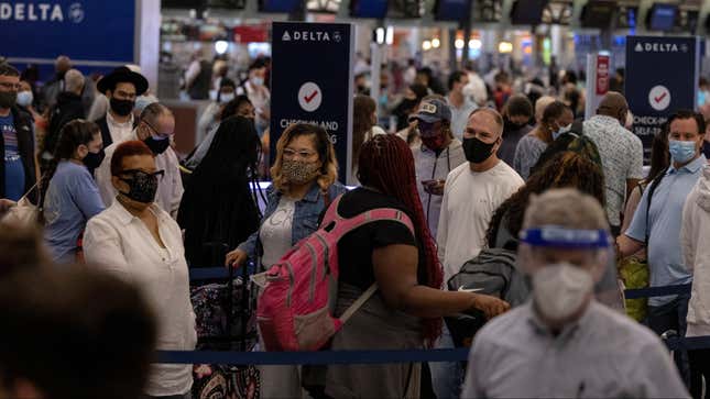 Travelers with masks on wait in line at a crowded US airport.