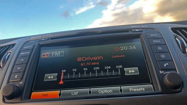 A photo of a car radio with clouds behind it. 