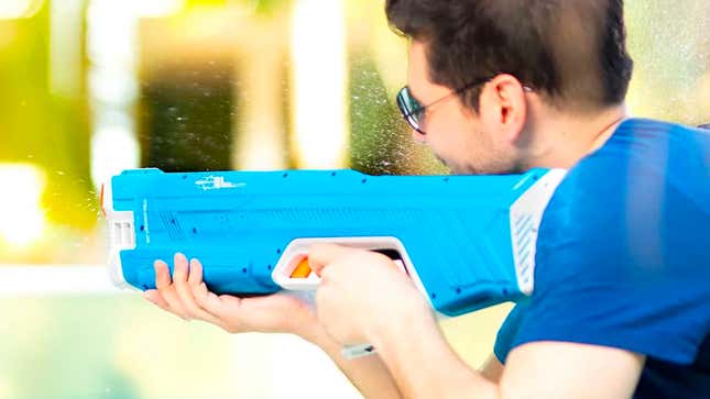 A user holding and firing a blue SpyraThree water blaster.