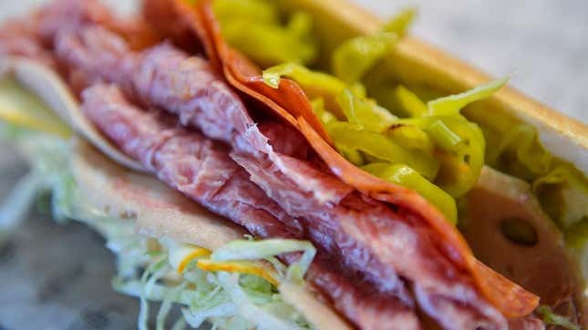 close-up shot of an Italian sub sandwich with meat, lettuce, pickled peppers, and vinegar