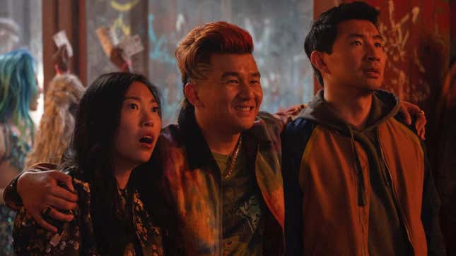 Awkwafina's Katy and Simu Liu's Shaun/Shang-Chi look at something in shock as Jon Jon (Ronny Chieng) smiles with his arms around their shoulders