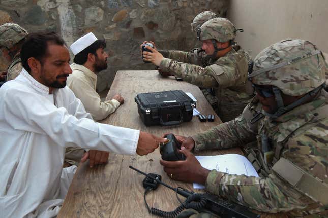 Photo of U.S. soldiers taking biometric data from people