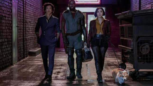 Spike Spiegel (John Cho), Jet Black (Mustafa Shakir), and Faye Valentine (Daniela Pineda) walking down an alley with Ein the dog. 