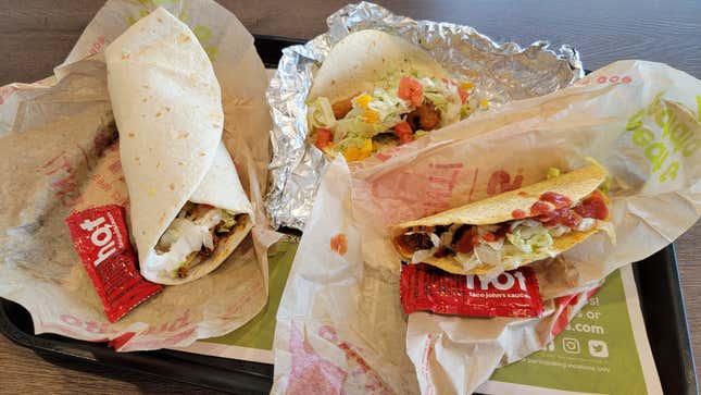 A burrito and two tacos from the Taco John's menu on a tray