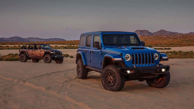 Two Jeep Wrangler Unlimited trucks parked on sand. 