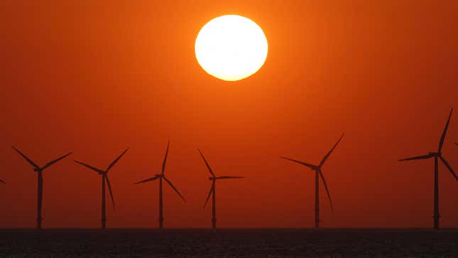 The sun sets behind the wind turbines of Burbo Bank Offshore Wind Farm in the Irish Sea on May 23, 2018.