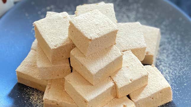 Pile of peanut butter marshmallows on a black plate dusted with peanut powder