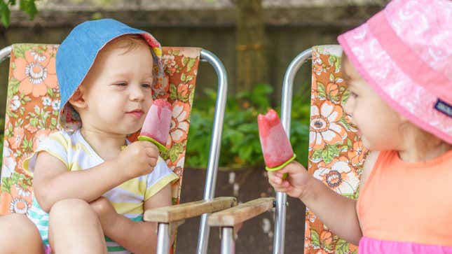 Two toddlers eating popsicles outside