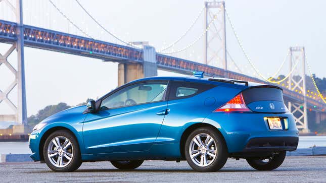 A photo of a blue Honda CR-Z sports car parked by a bridge. 