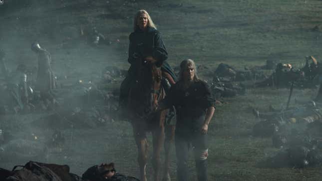 Geralt, on foot, leads Ciri and her horse across a smoky battlefield littered with corpses.