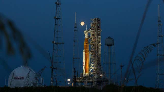 Una Luna llena brilla de fondo mientras el cohete SLS se alza sobre el Complejo de Lanzamiento 39B en el Centro Espacial Kennedy de la NASA en Florida. 14 de junio de 2022.