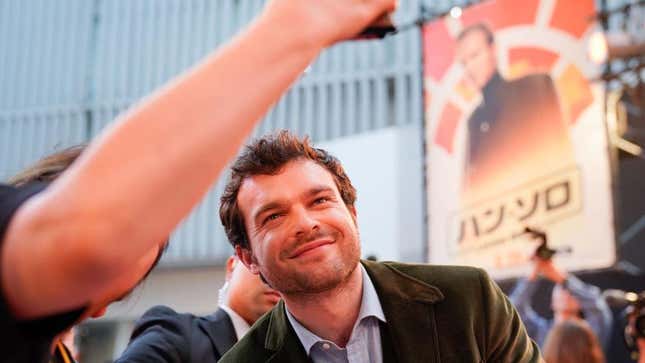 Alden Ehrenreich takes a selfie with a fan on the red carpet.