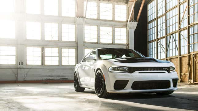 A photo of a white Dodge Charger hellcat in a hanger. 
