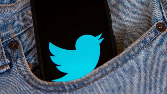 A phone with a blue bird symbol on it in a jeans pocket.
