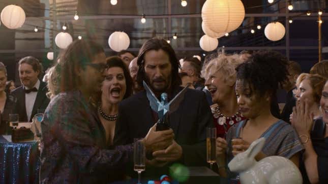 Keanu Reeves as Thomas Anderson holds a Game Award, looking somewhat lost in life, while people around him appear celebratory.