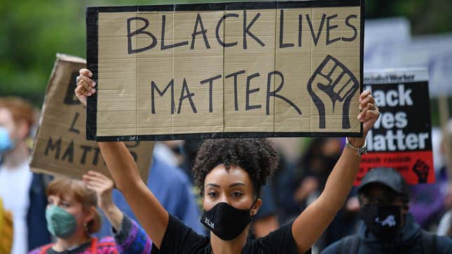 People hold up placards in support of the Black Lives Matter movement as they take part in the inaugural Million People March march from Notting Hill to Hyde Park in London on August 30, 2020, to put pressure on the UK Government into changing the “UK’s institutional and systemic racism.”