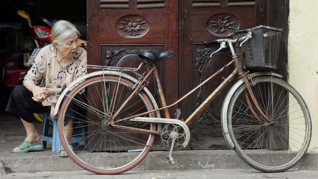 A photo of a vintage Peugeot bike leaning on a door. 
