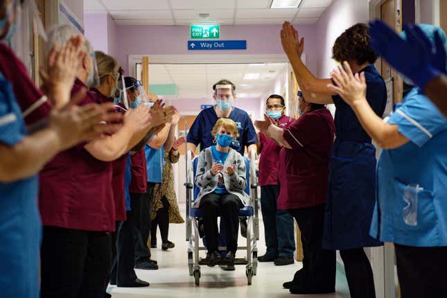 Staff applauds Margaret Keenan on her wheelchair