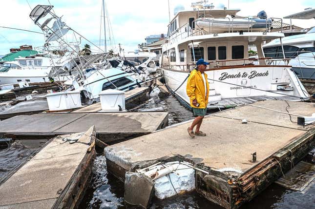 A man inspects damage to a marina as boats are partially submerged in the aftermath of Hurricane Ian in Fort Myers, Florida, on September 29, 2022.